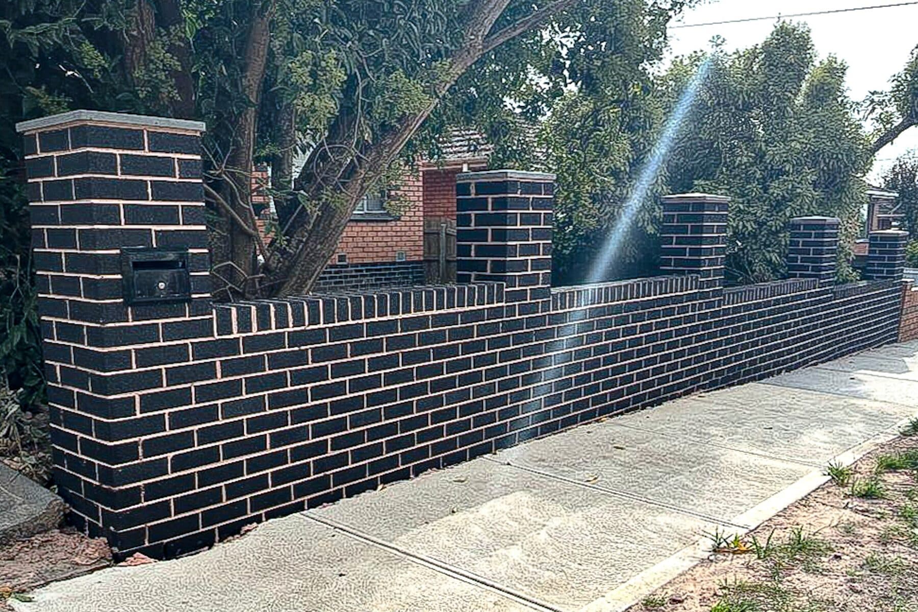 Charcoal brick front fence with piers, capping and a built-in letterbox