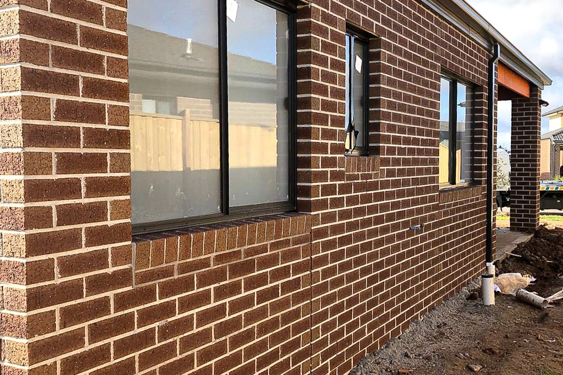 Brown brindle face brick wall with flush sills and black-framed windows